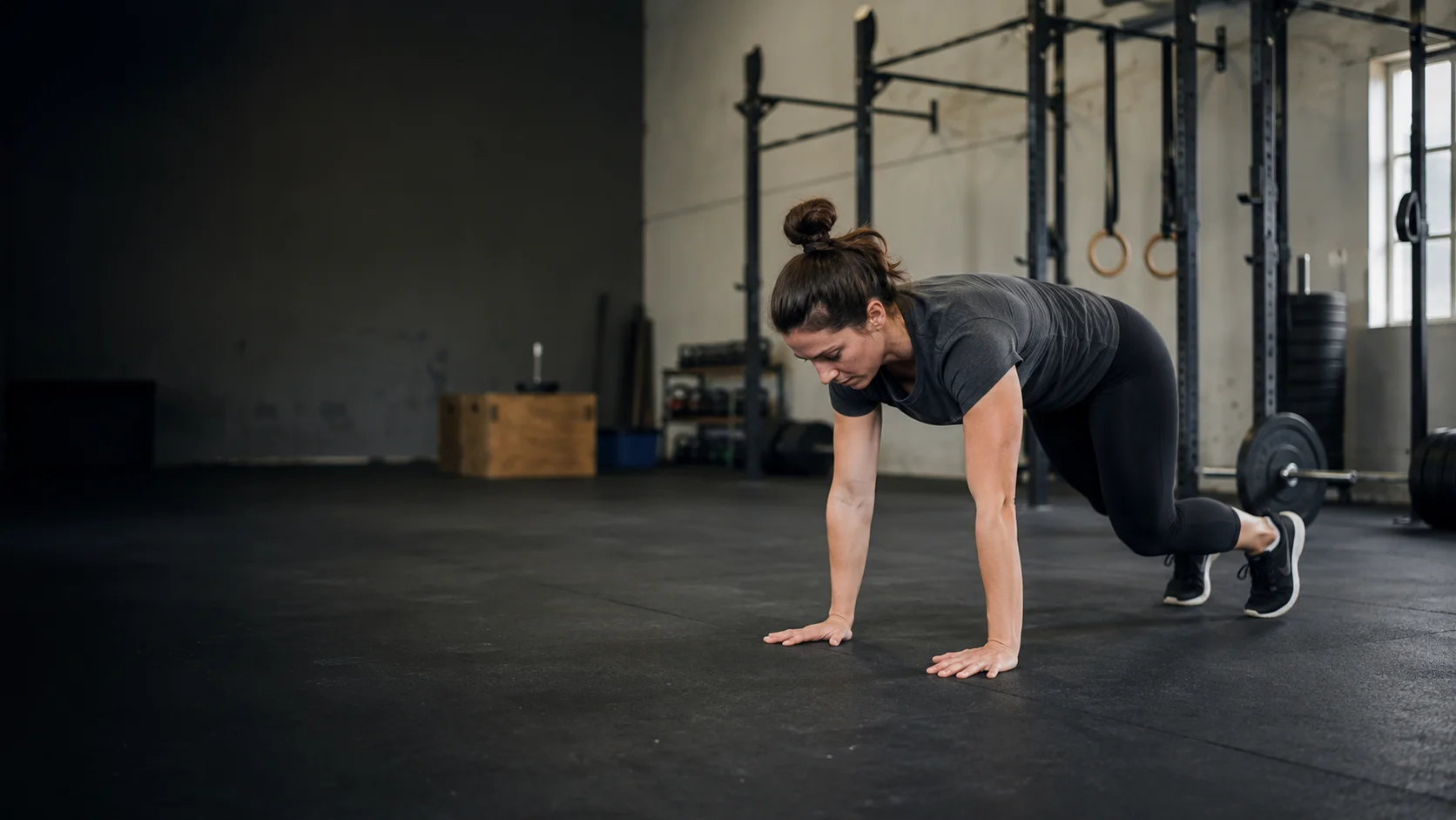 Persona principiante realizando un burpee controlado en un box de CrossFit